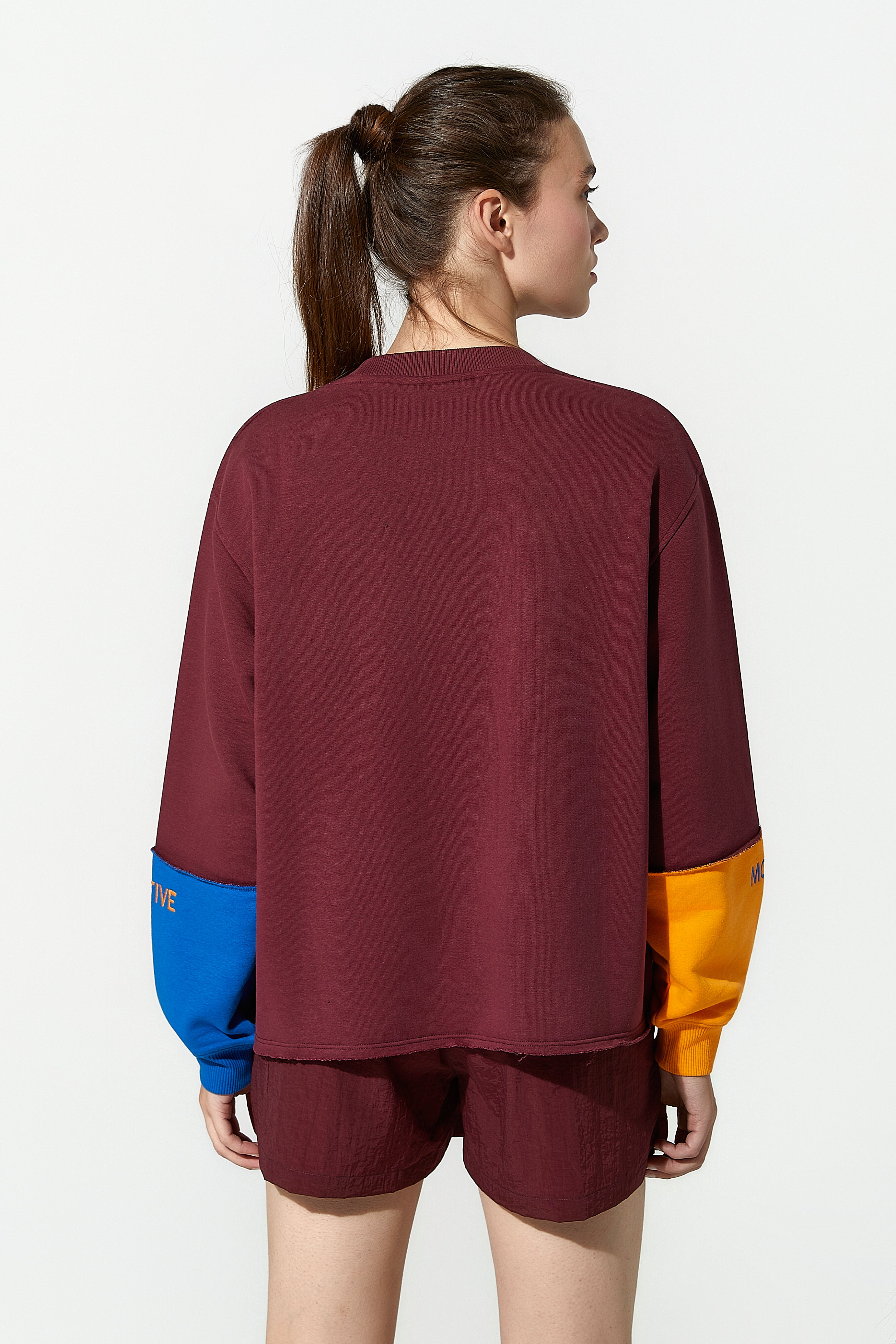 A model wearing a burgundy oversized sweatshirt