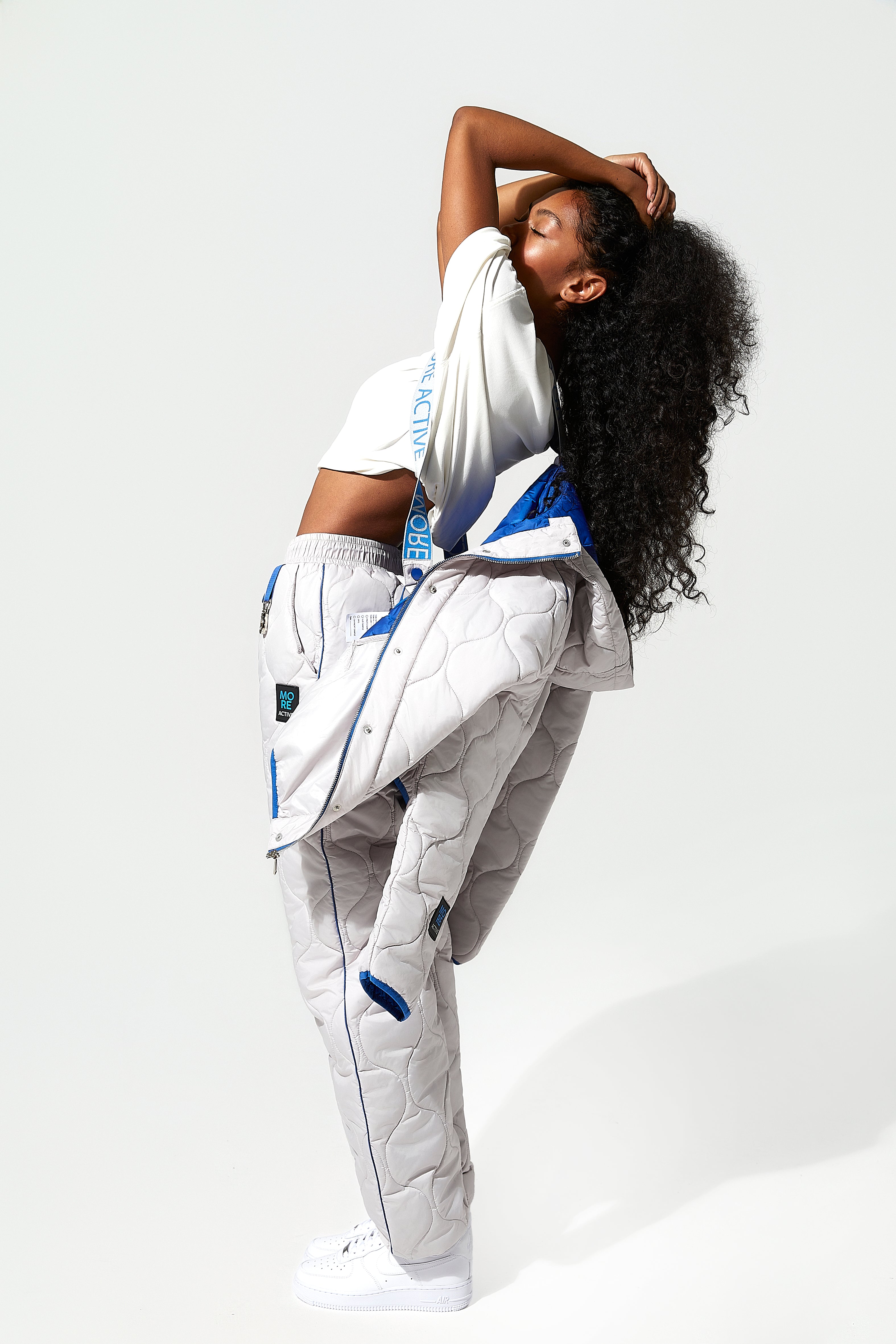 A model wearing an ice white puffer jacket and quilted trousers with blue detailing