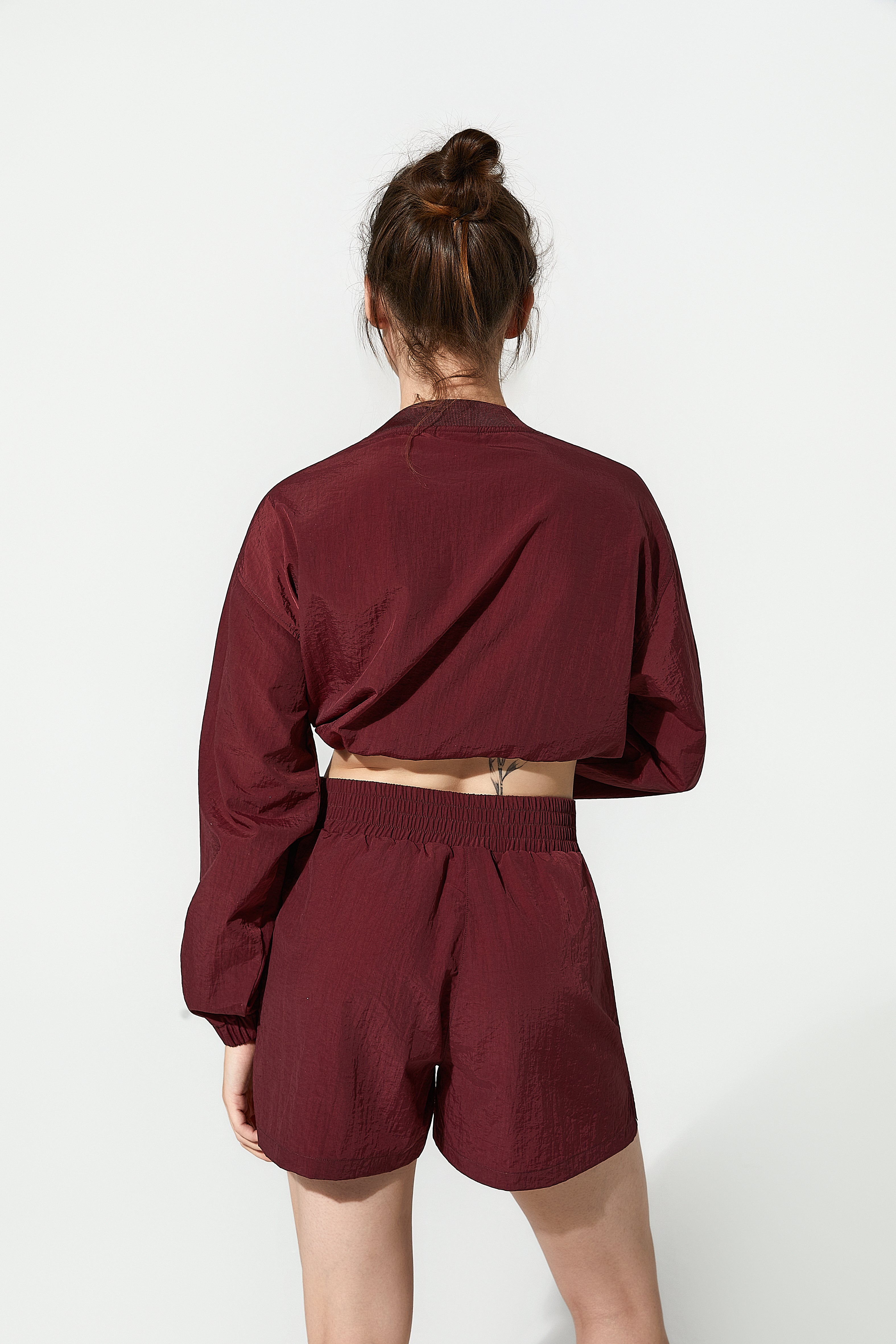 Burgundy top windbreakers for women over matching sports shorts, capturing the essence of a functional womens windbreaker designed for active women