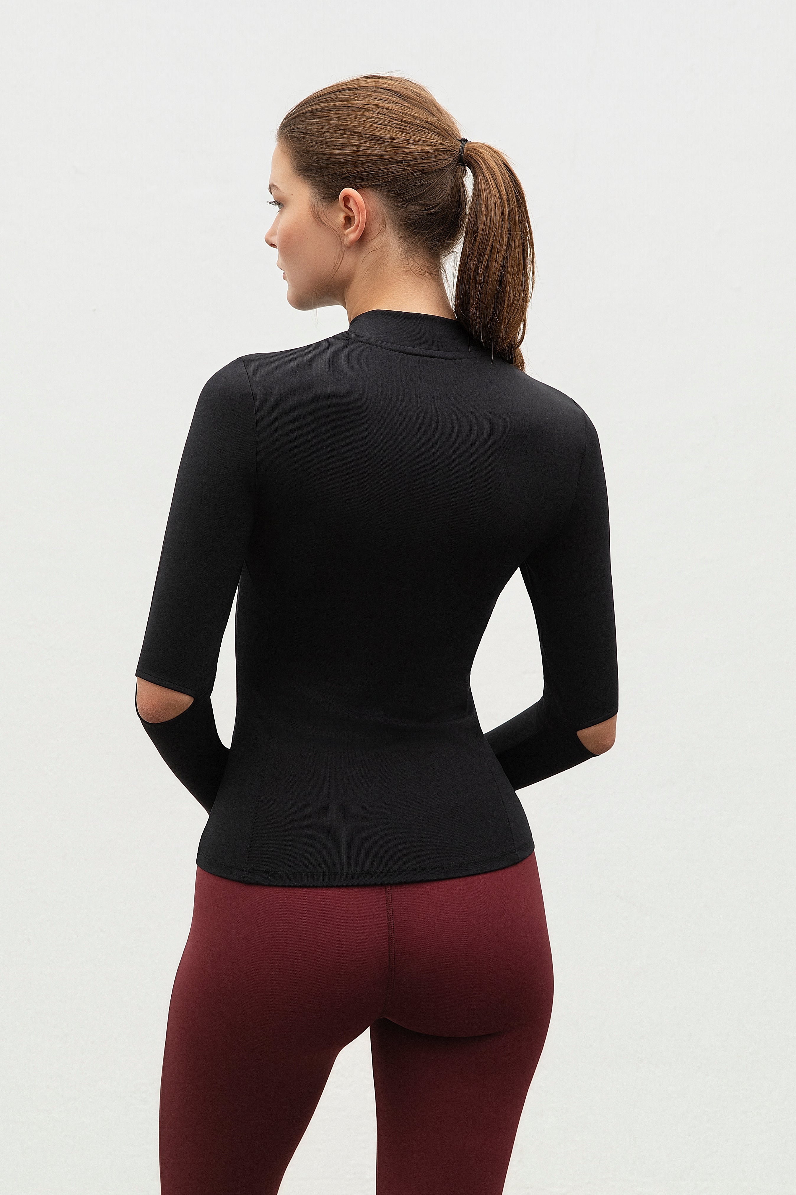 Model wearing  More Activewear's  black long-sleeve top and maroon leggings on a white background