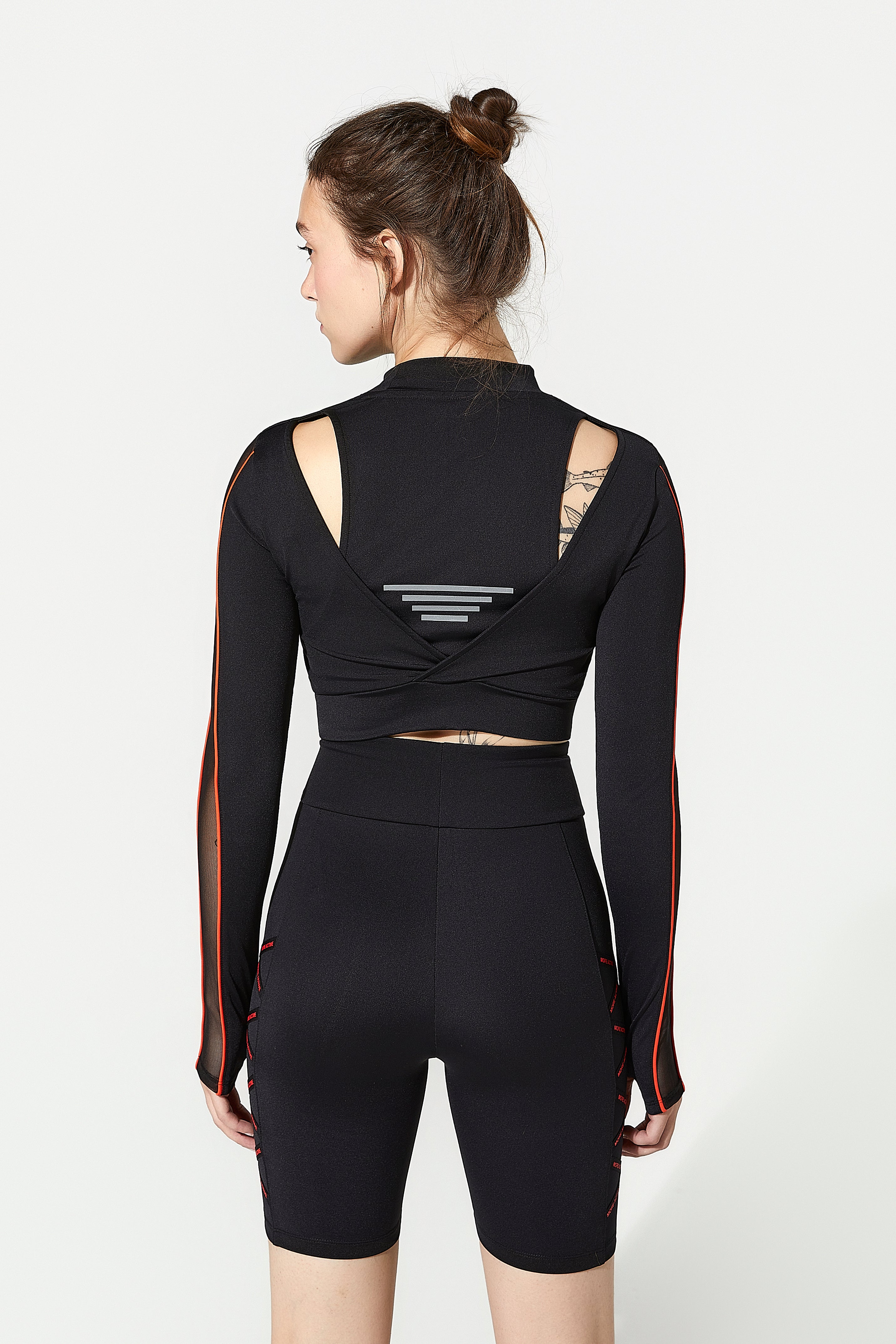 Model wearing a black athletic gym top with orange accents and working out shorts for women​ - sports shorts​