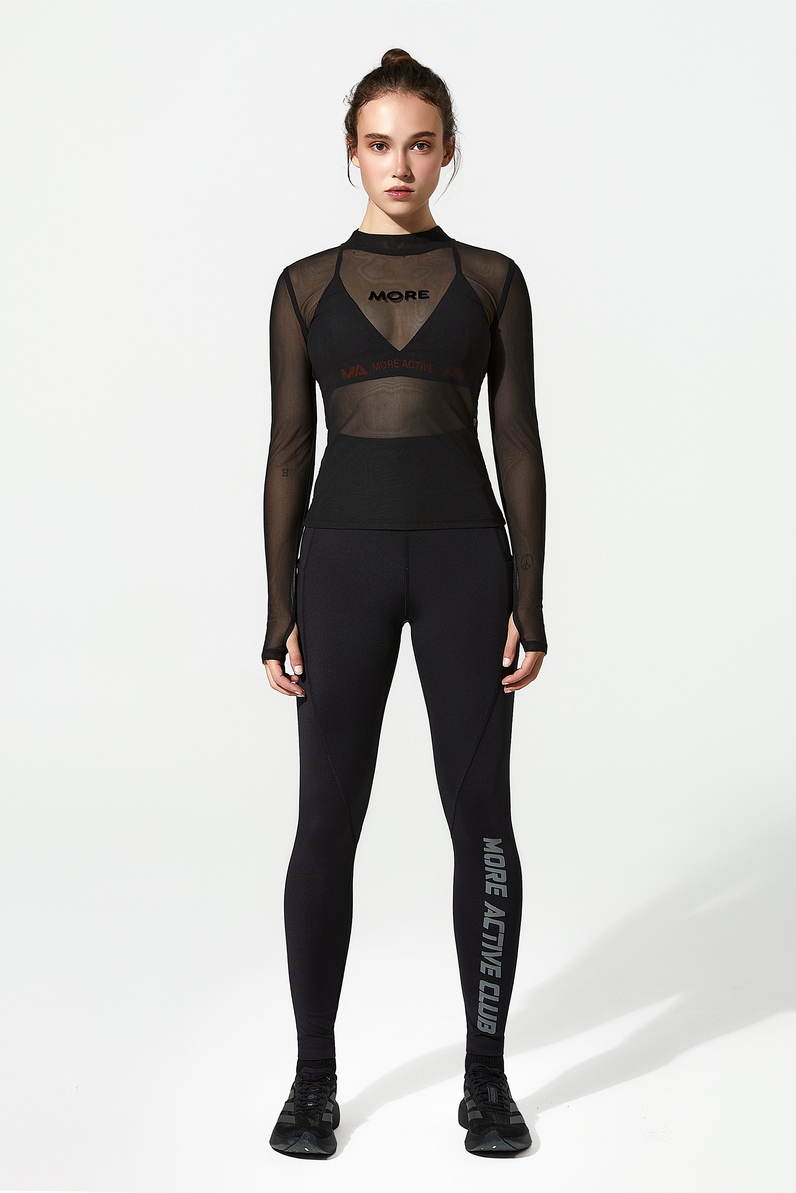 Model wearing a black ladies activewear outfit with sheer panels and text on a white background