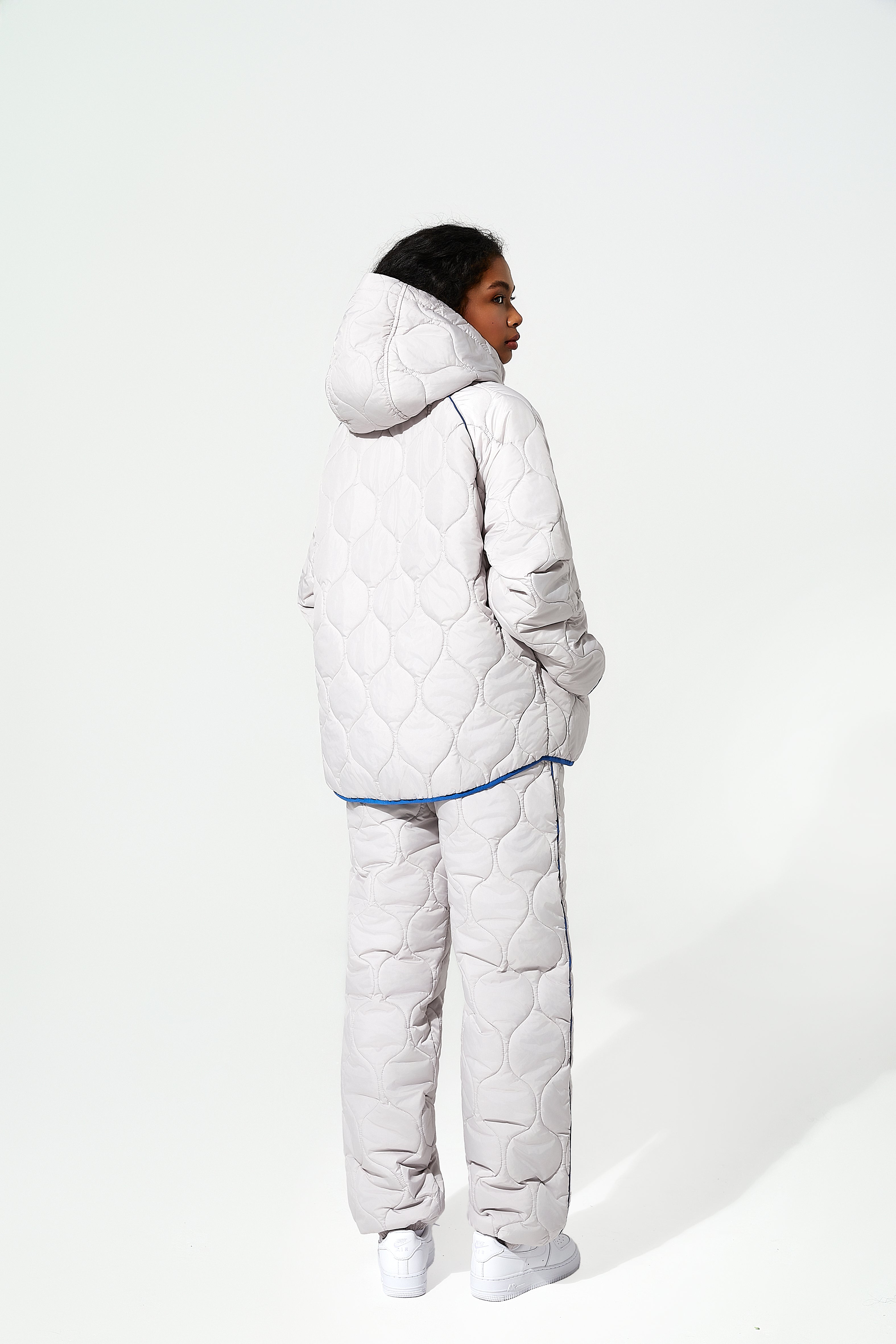 Person wearing a white puffer jacket and quilted trousers
