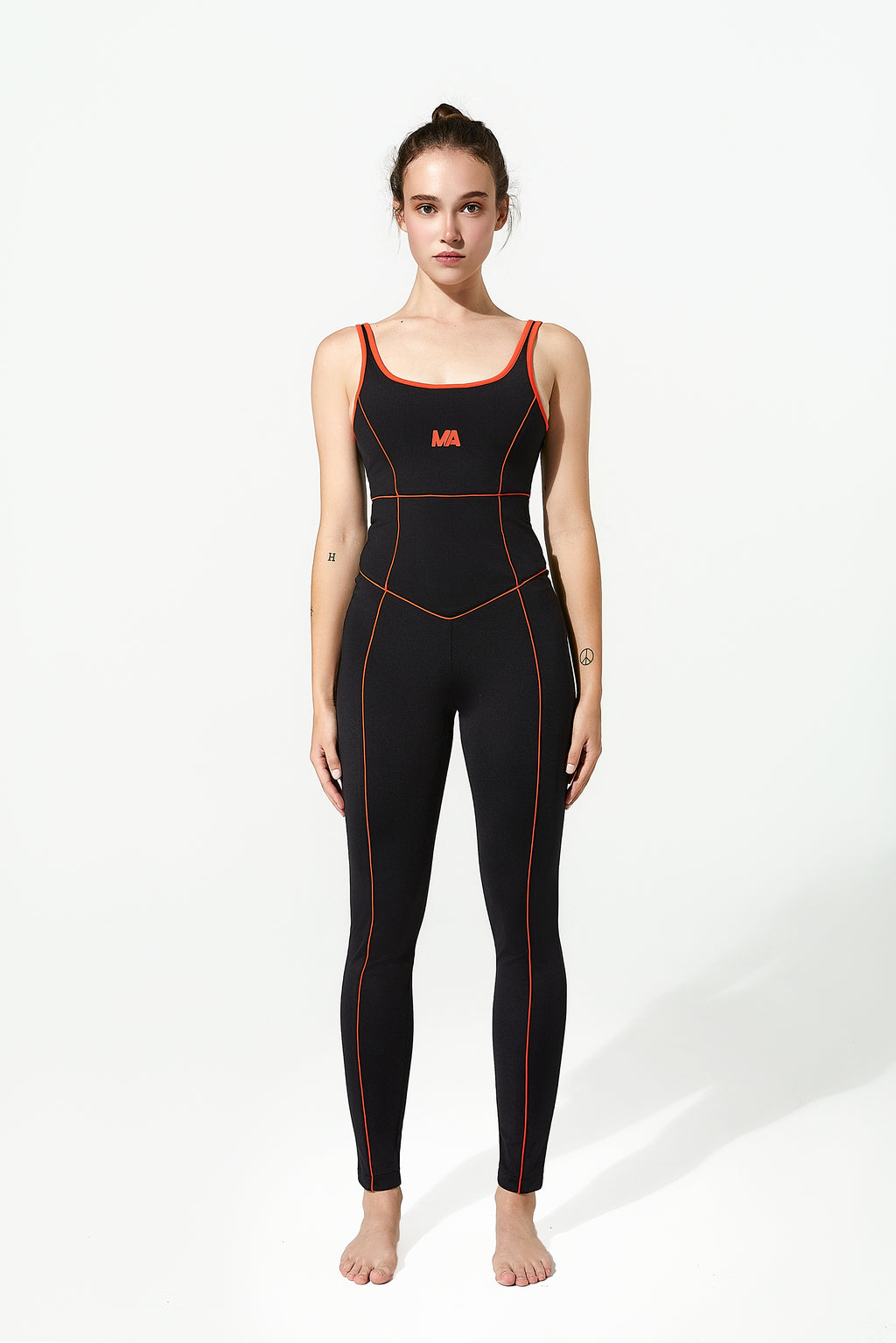Woman wearing a black gym unitard with red accents on a white background