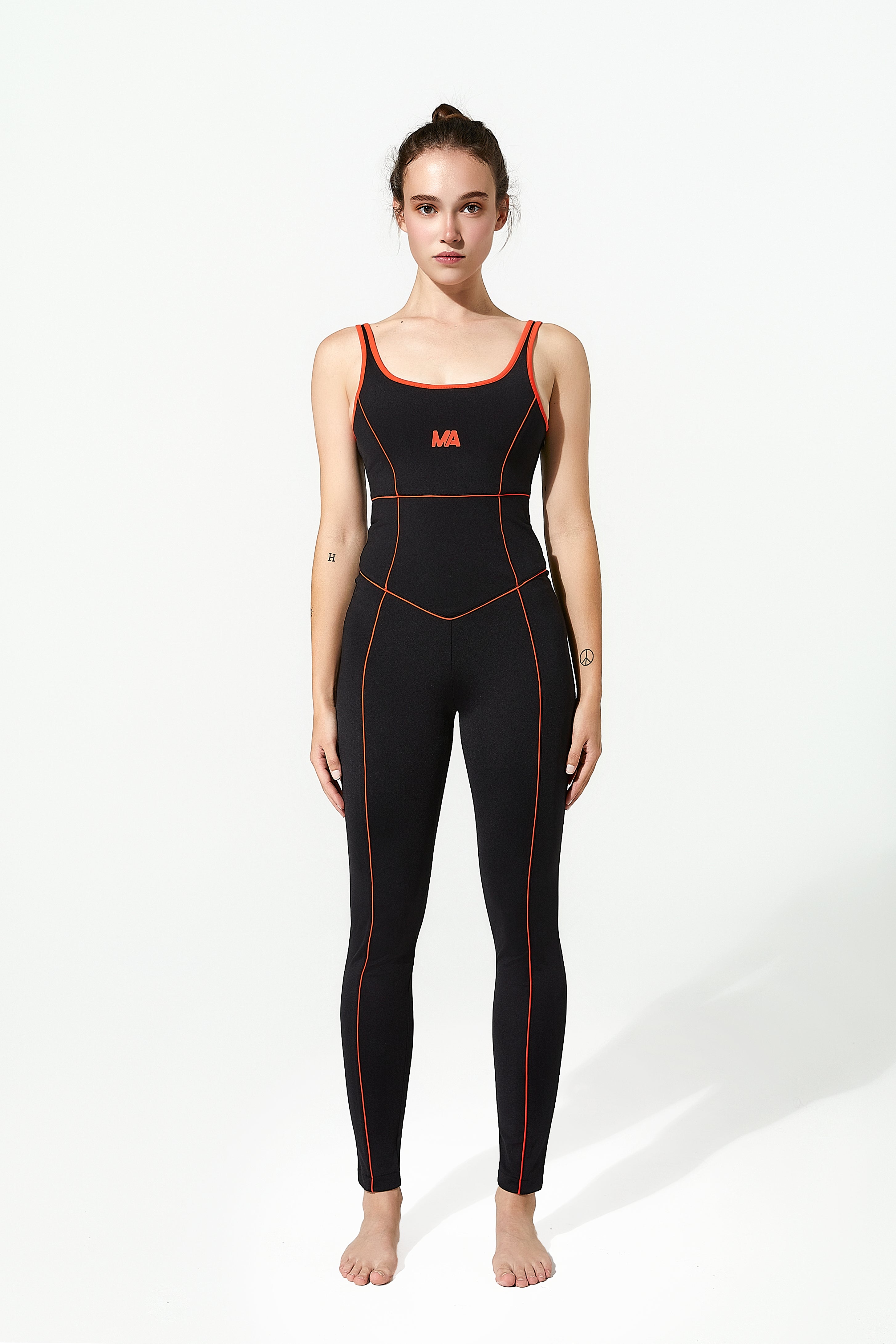 Woman wearing a black gym unitard with red accents on a white background