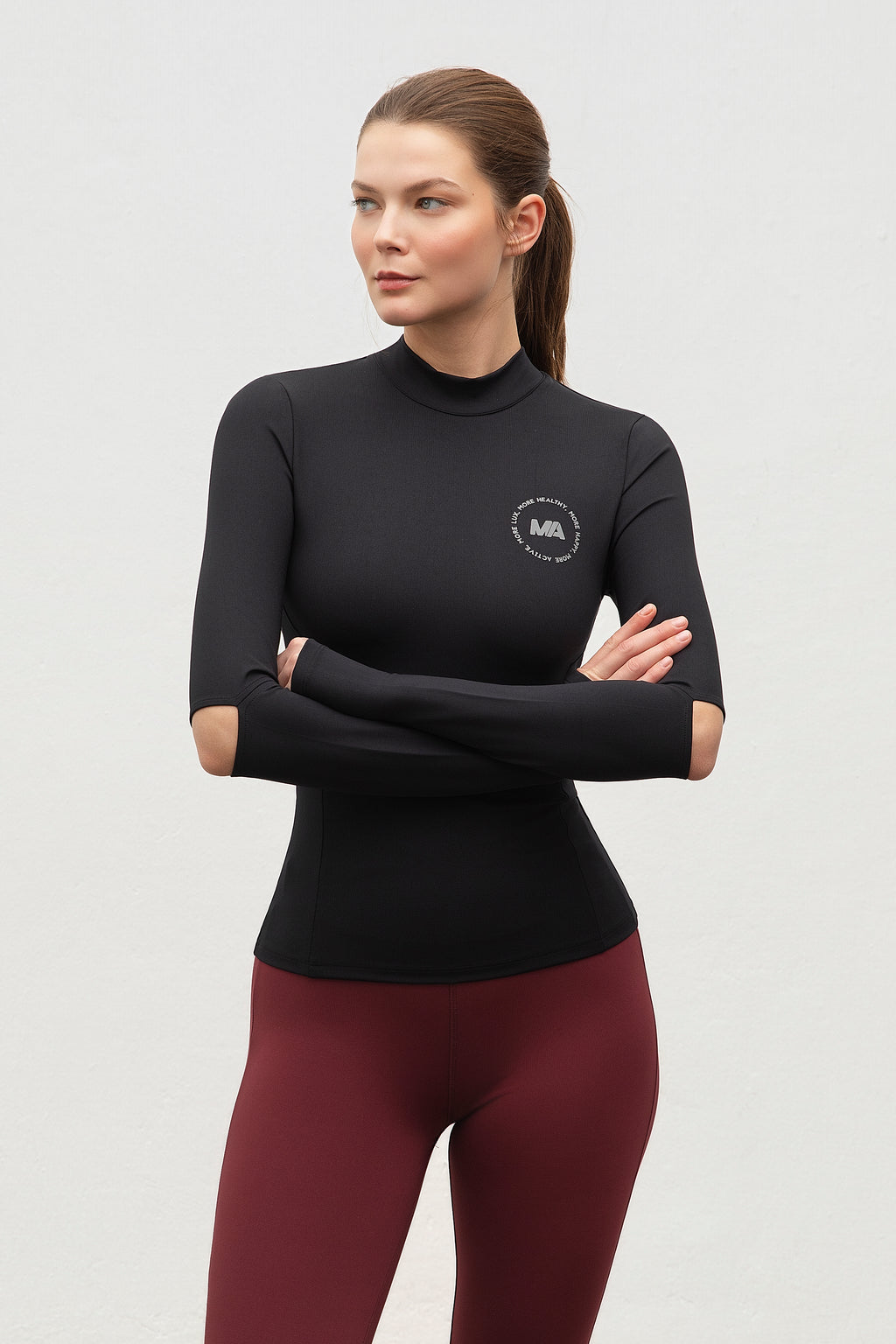Woman wearing a black running top and maroon leggings with More Activewear logo on.