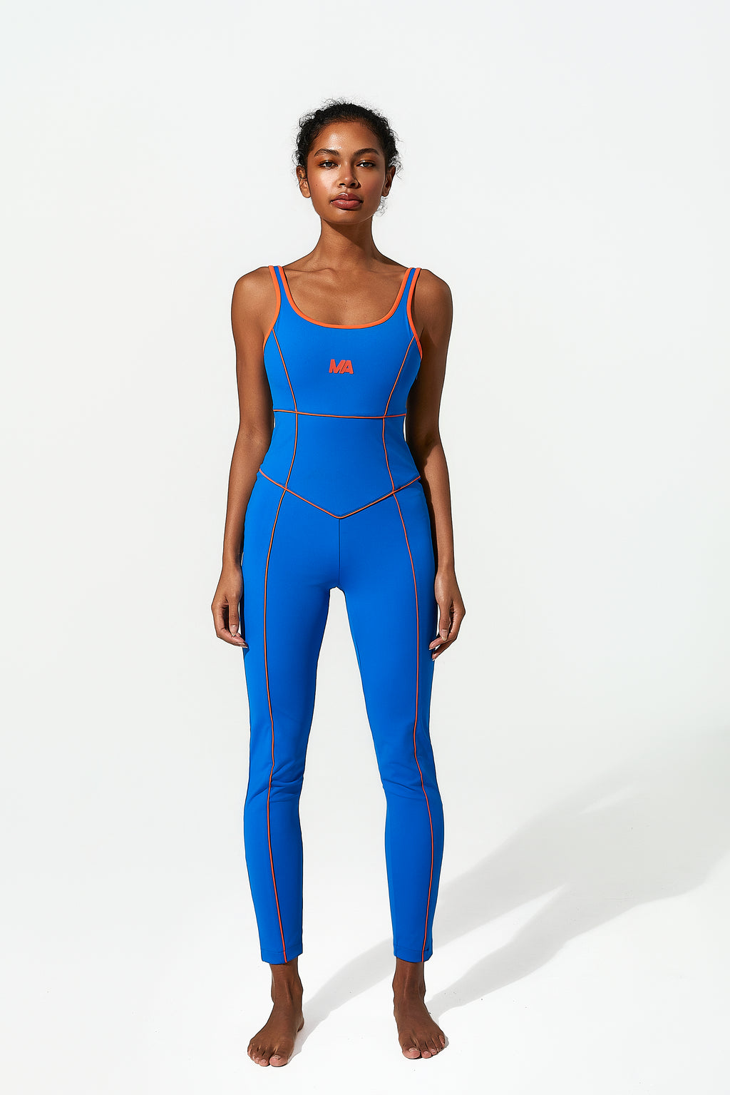 Woman wearing a blue  bodysuit with orange piping, front view on a white background
