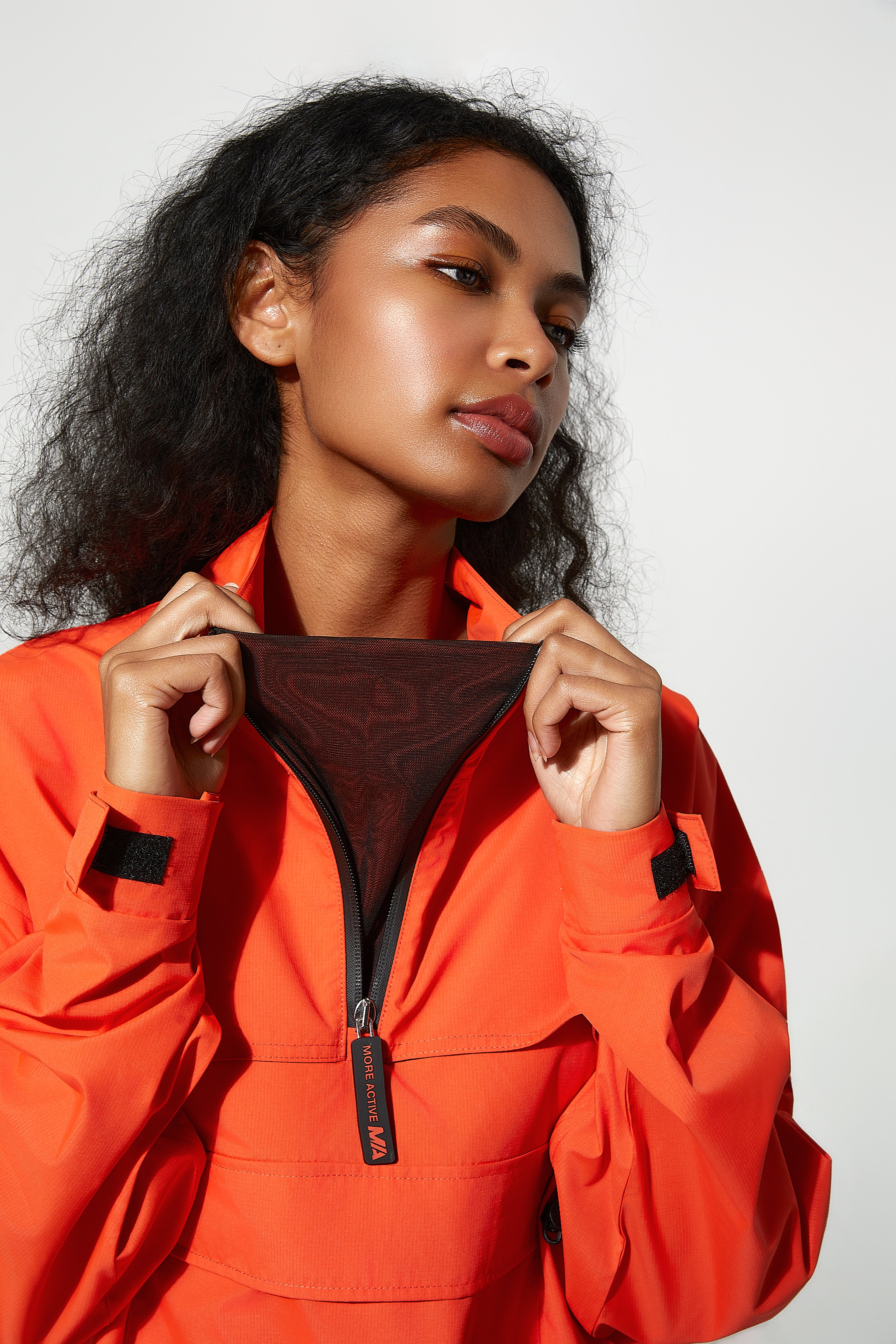 Woman wearing waterproof windbreaker orange jacket with a white background