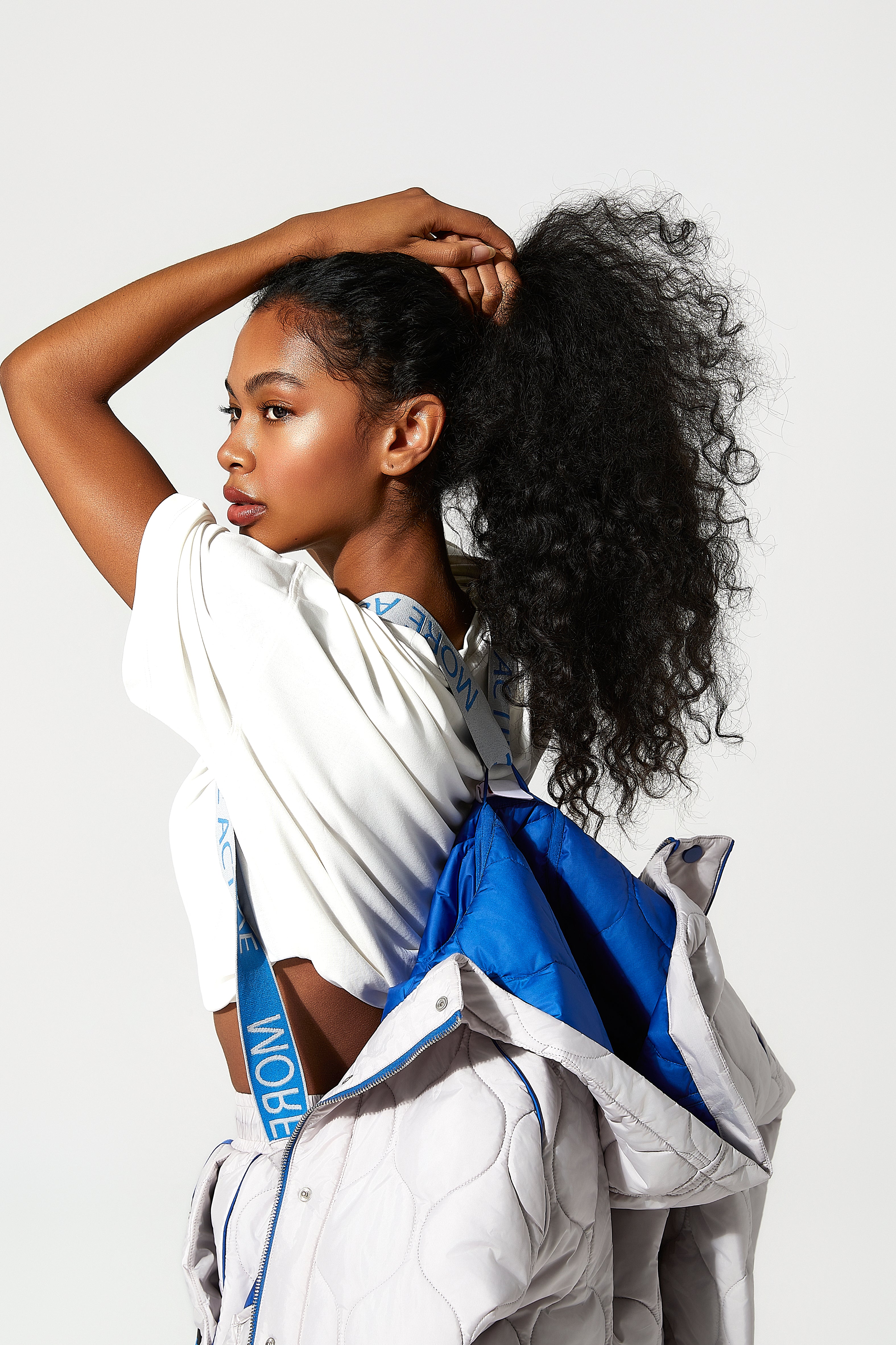 Woman with a blue quilted puffer jacket , the the suspenders with More Active branding over her shoulders 