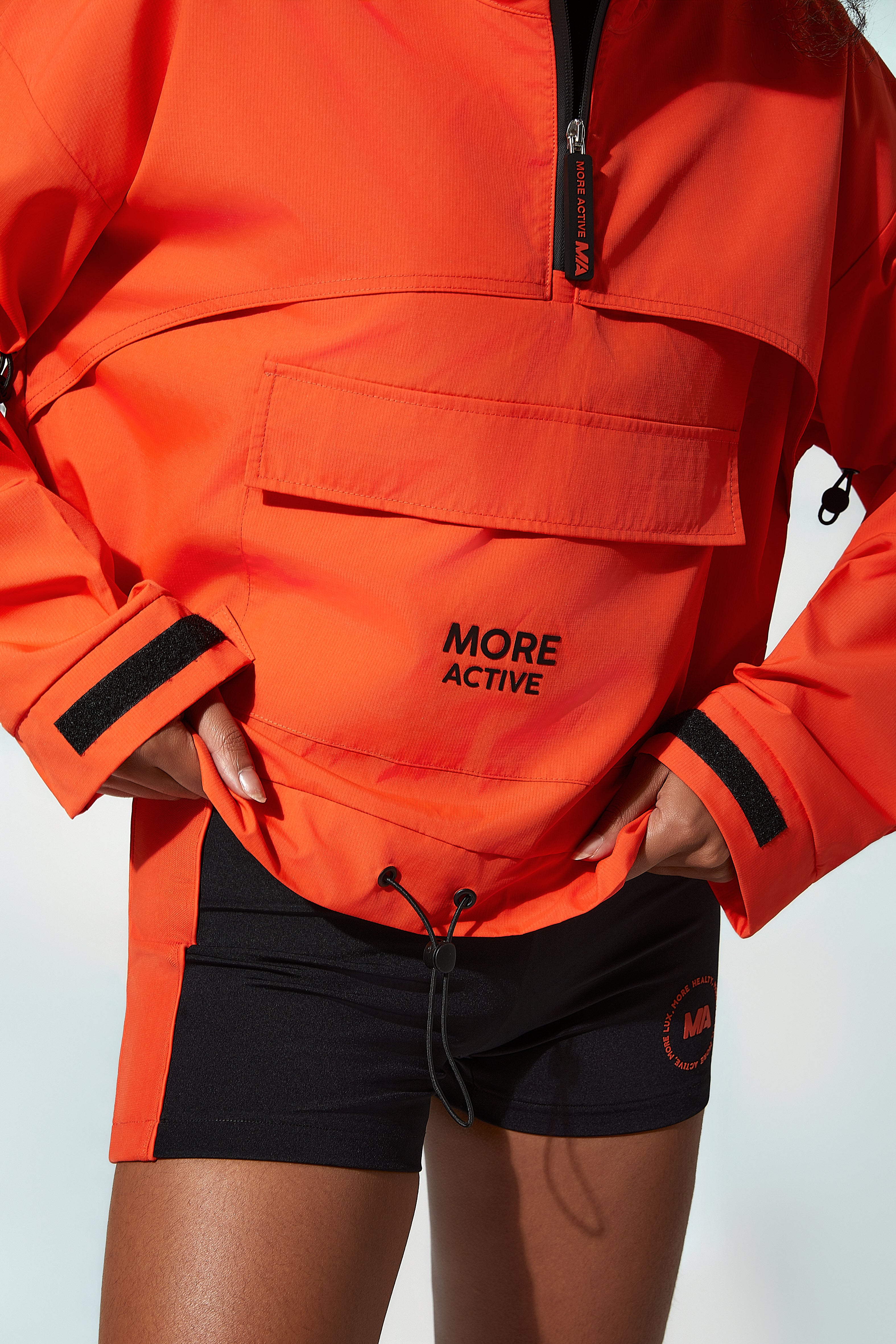 Women wearing an orange windbreaker jacket with a visible brand logo.
