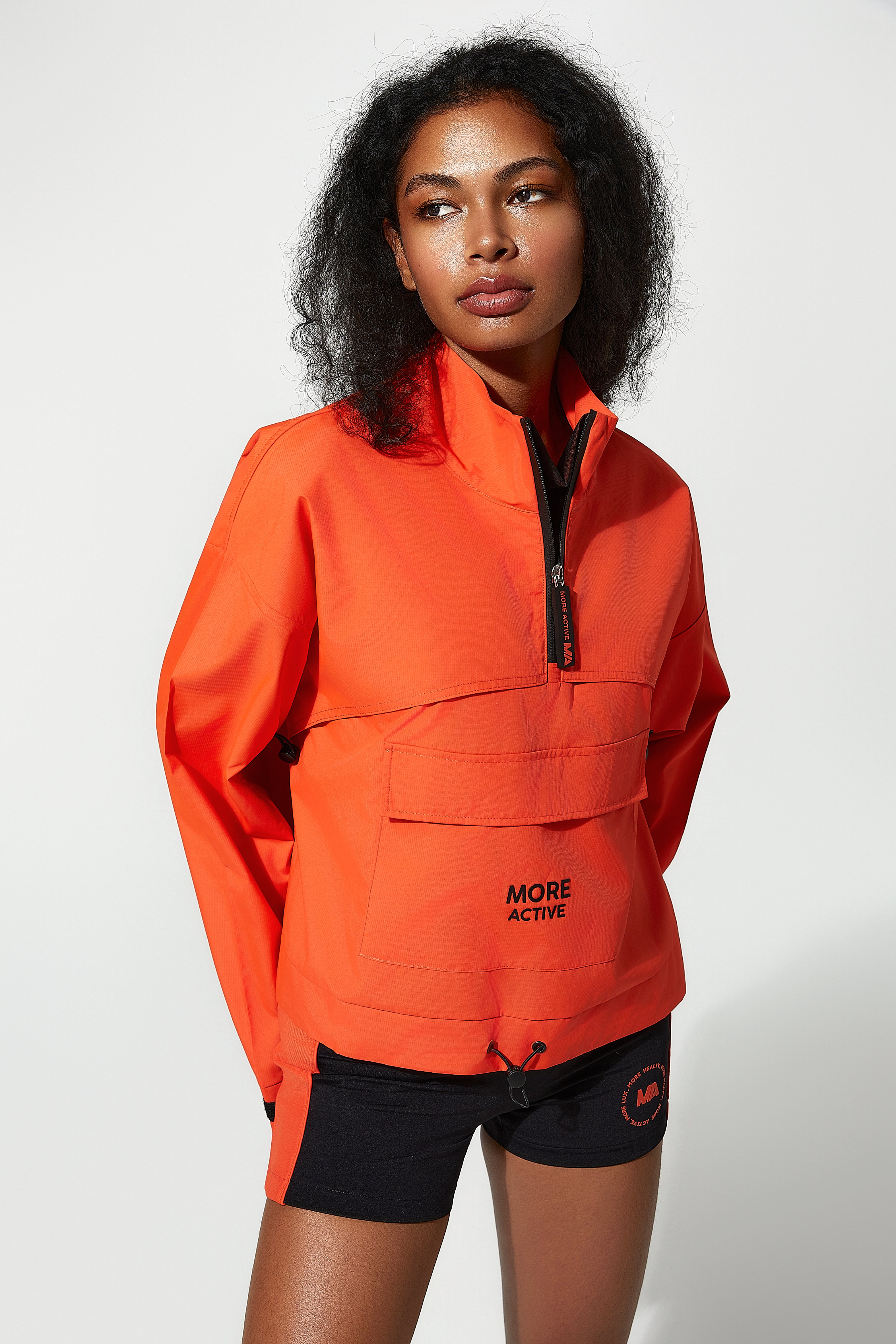 a model wearing a womens windbreaker​orange jacket with 'More Active' branding 