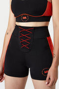 Black athletic shorts with red side panels and red lace-up front detail, shown on a model against a light gray studio background.