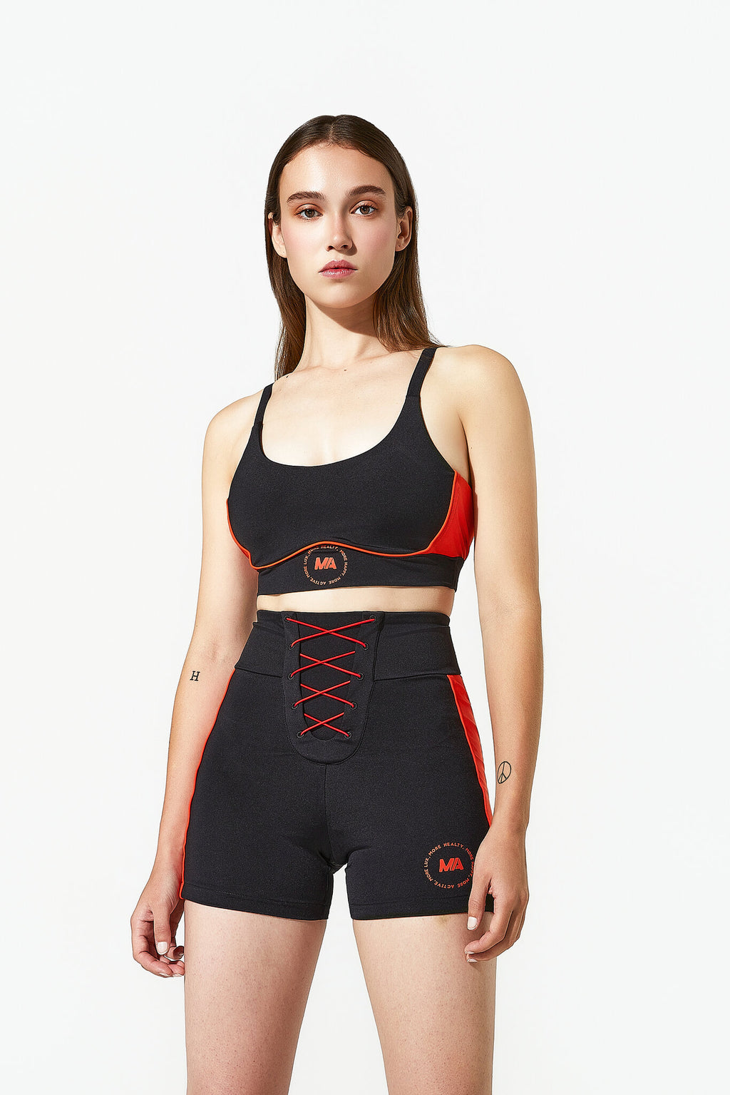 Woman wearing a black sports bra and shorts with red accents on a white background