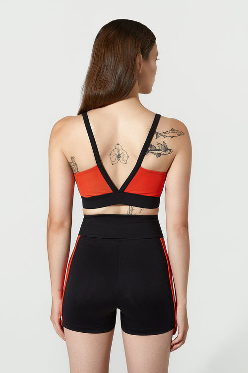 Woman wearing a black and red sports outfit with tattoos visible on her back.