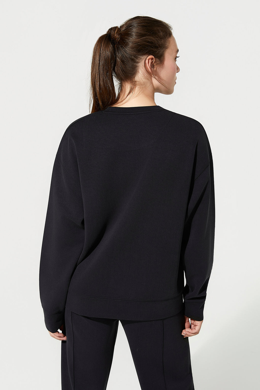 Person wearing a black sweatshirt and pants on a white background