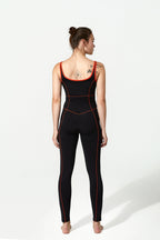 Woman wearing a black bodysuit with red accents on a white background