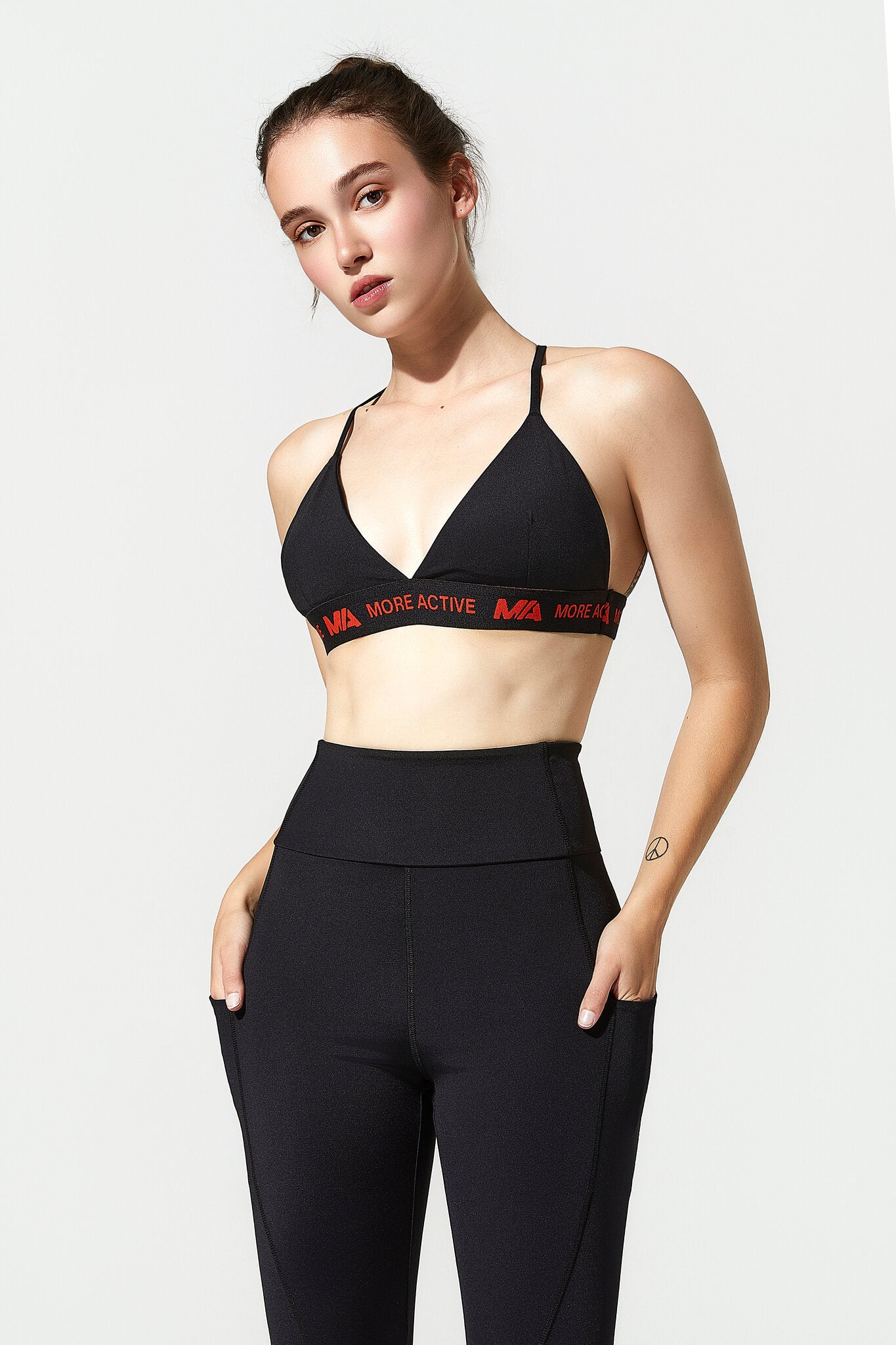 Woman wearing a black sports bra and leggings with a visible brand logo on a white background