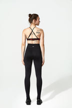 Woman wearing a black sports bra and leggings on a white background