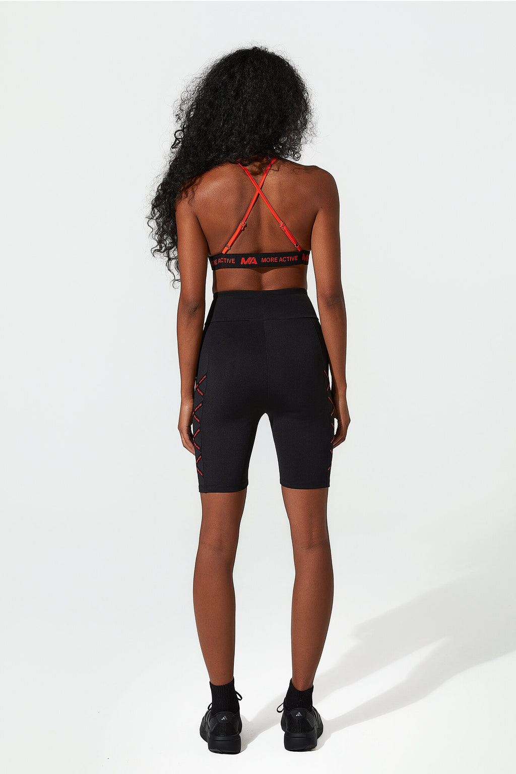 Person wearing a black sports bra and shorts with red accents on a white background