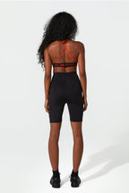 Person wearing a black sports bra and shorts with red accents on a white background