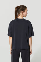 Person wearing a black t-shirt and pants on a light gray background