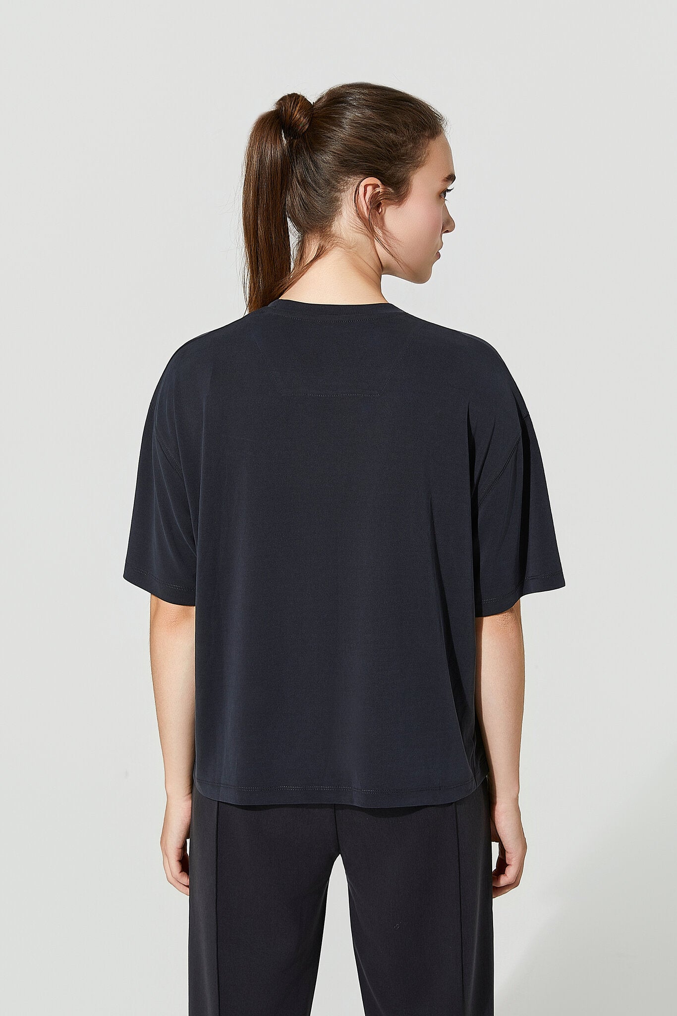 Person wearing a black t-shirt and pants on a light gray background