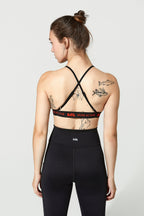 Woman wearing a black sports bra and leggings with visible branding on a light gray background