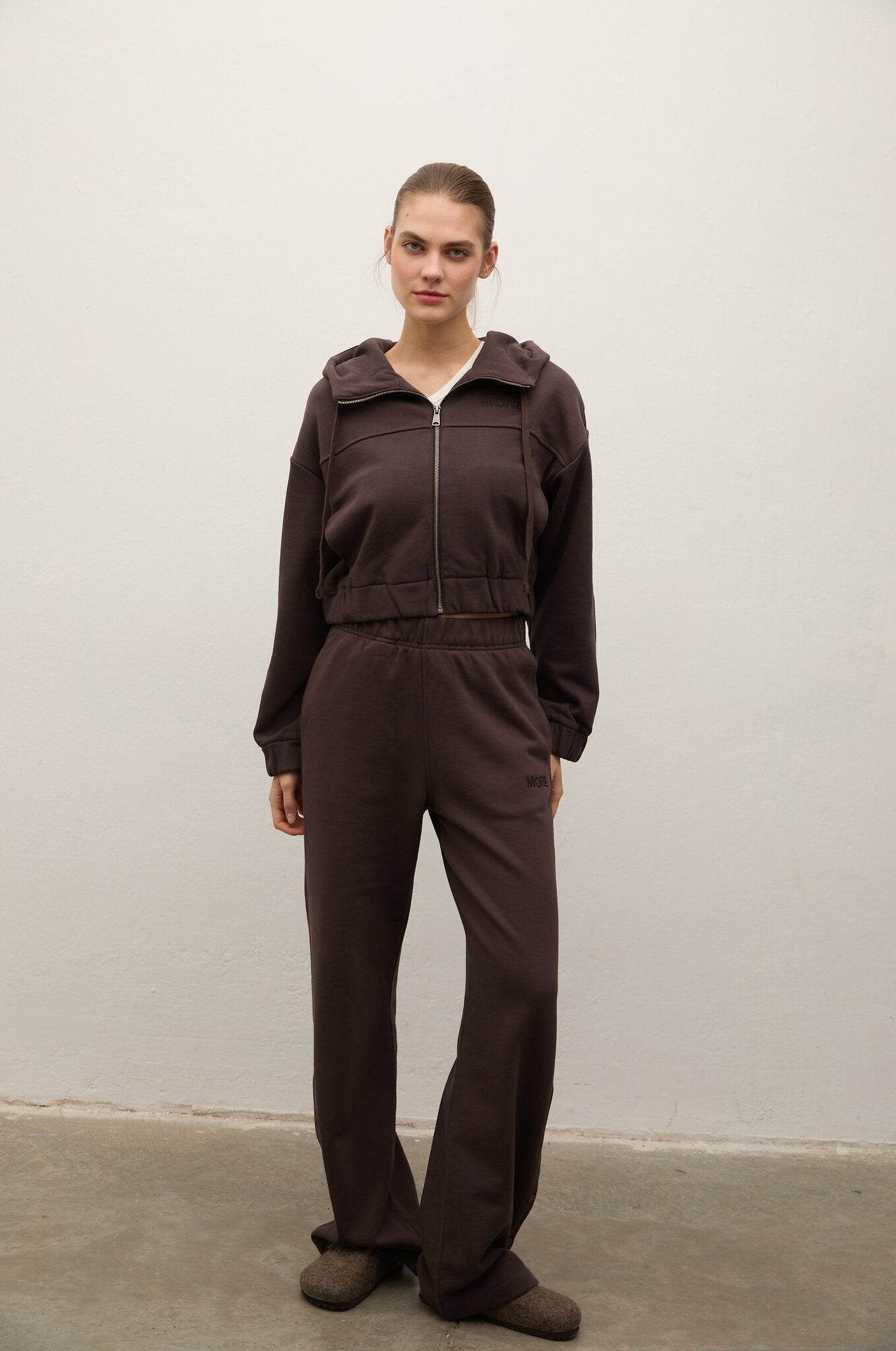 Person wearing a brown tracksuit against a plain background