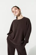 Person wearing a brown sweatshirt and pants on a white background