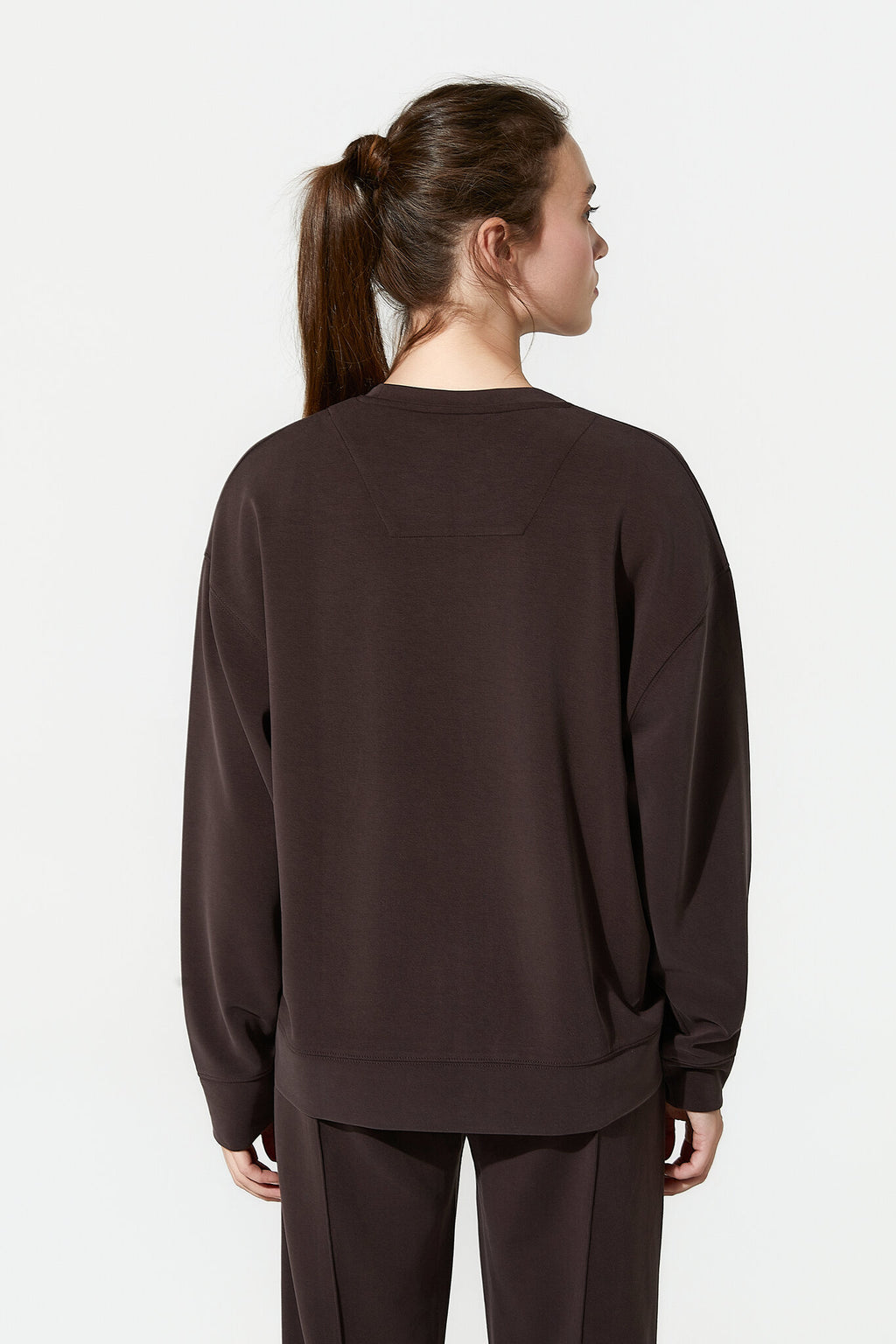 Person wearing a brown sweatshirt and pants on a white background