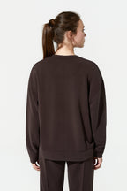 Person wearing a brown sweatshirt and pants on a white background