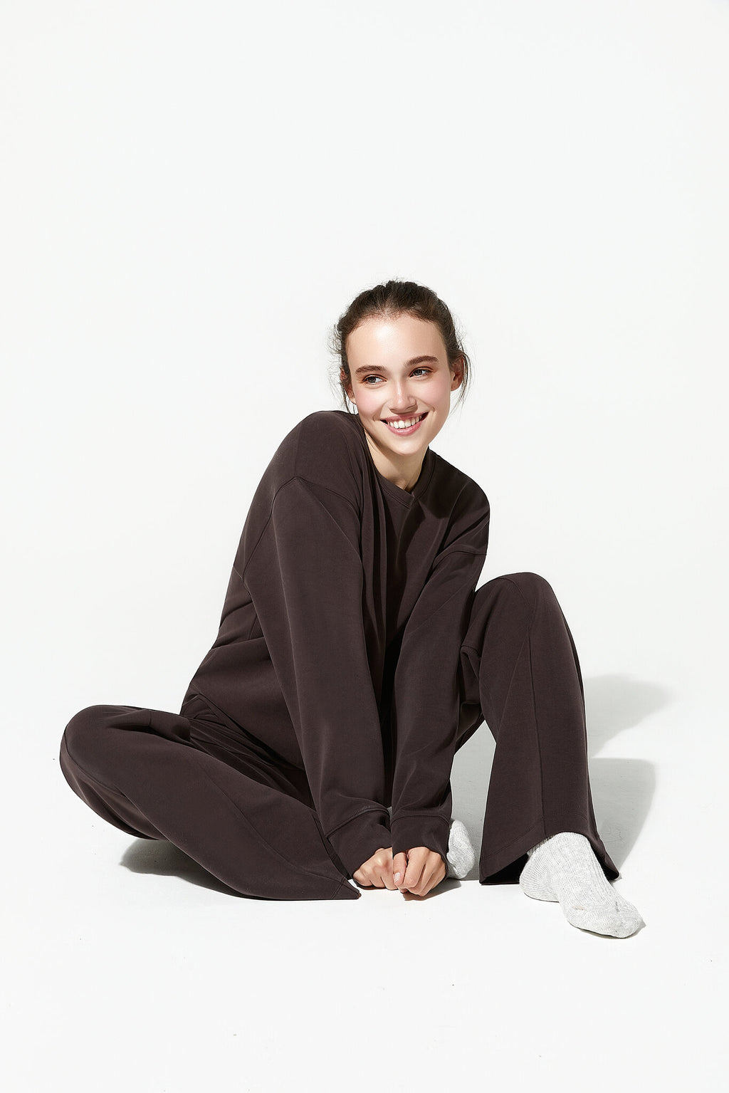 Person wearing a brown outfit sitting on a white background