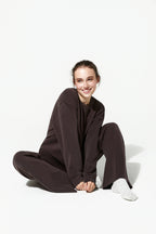 Person wearing a brown outfit sitting on a white background