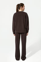 Person wearing a brown sweatshirt and pants on a white background