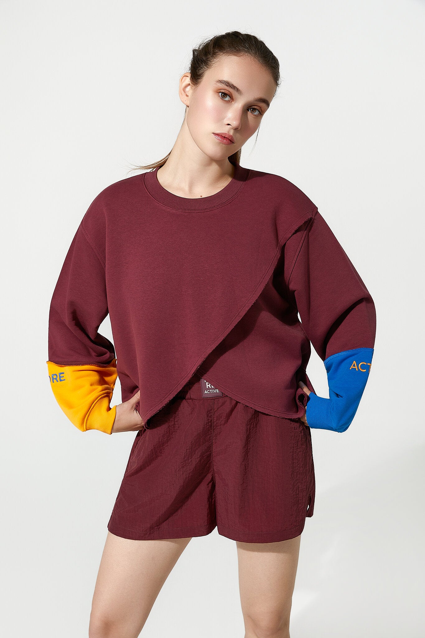 Person wearing a maroon outfit with colorful sleeves on a white background