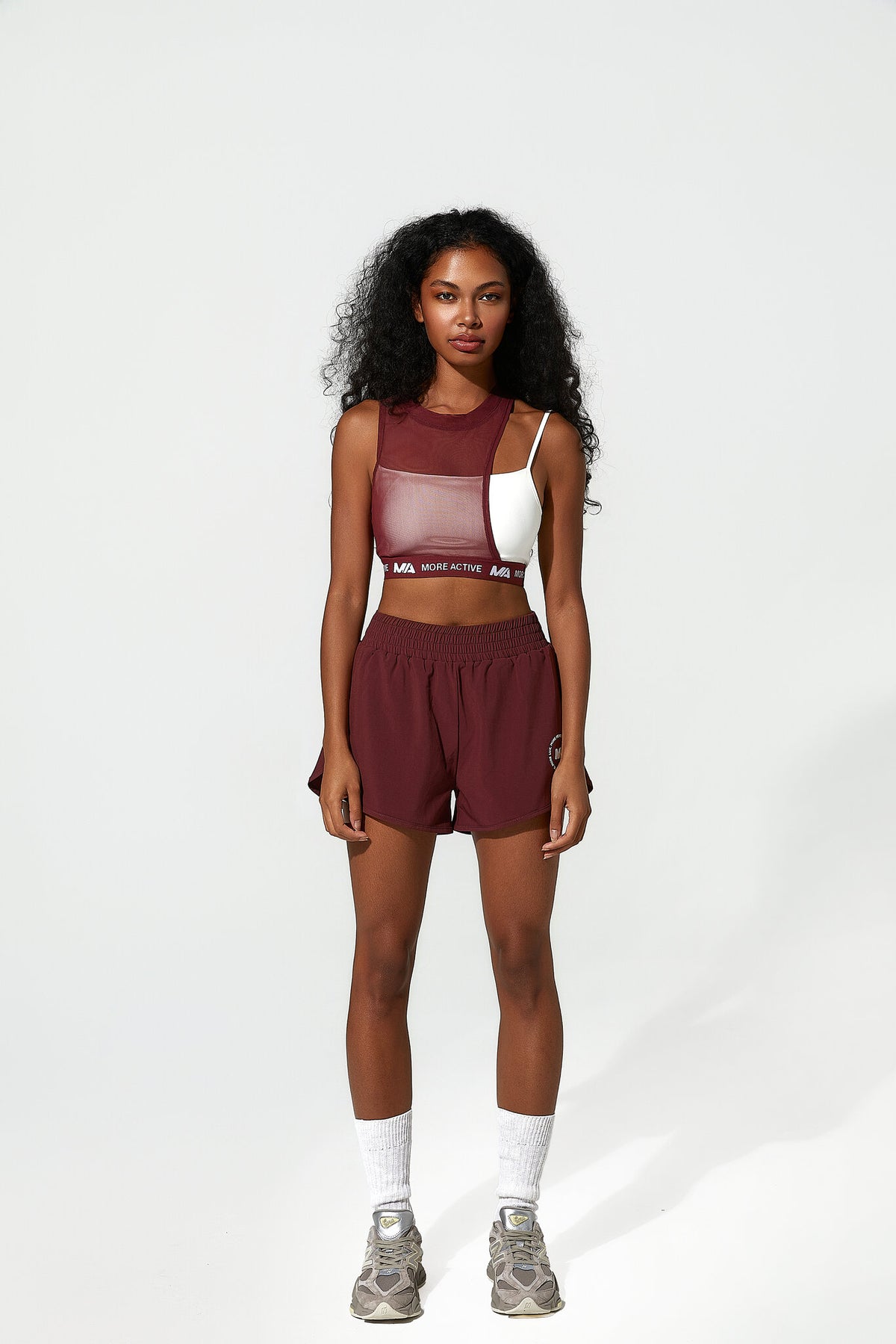 Woman wearing a maroon athletic outfit with a white background