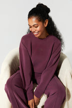 Woman wearing a burgundy outfit sitting on a white chair against a light gray background