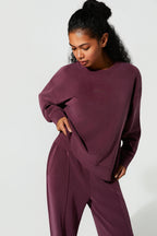 Woman wearing a maroon sweatshirt and pants set on a white background