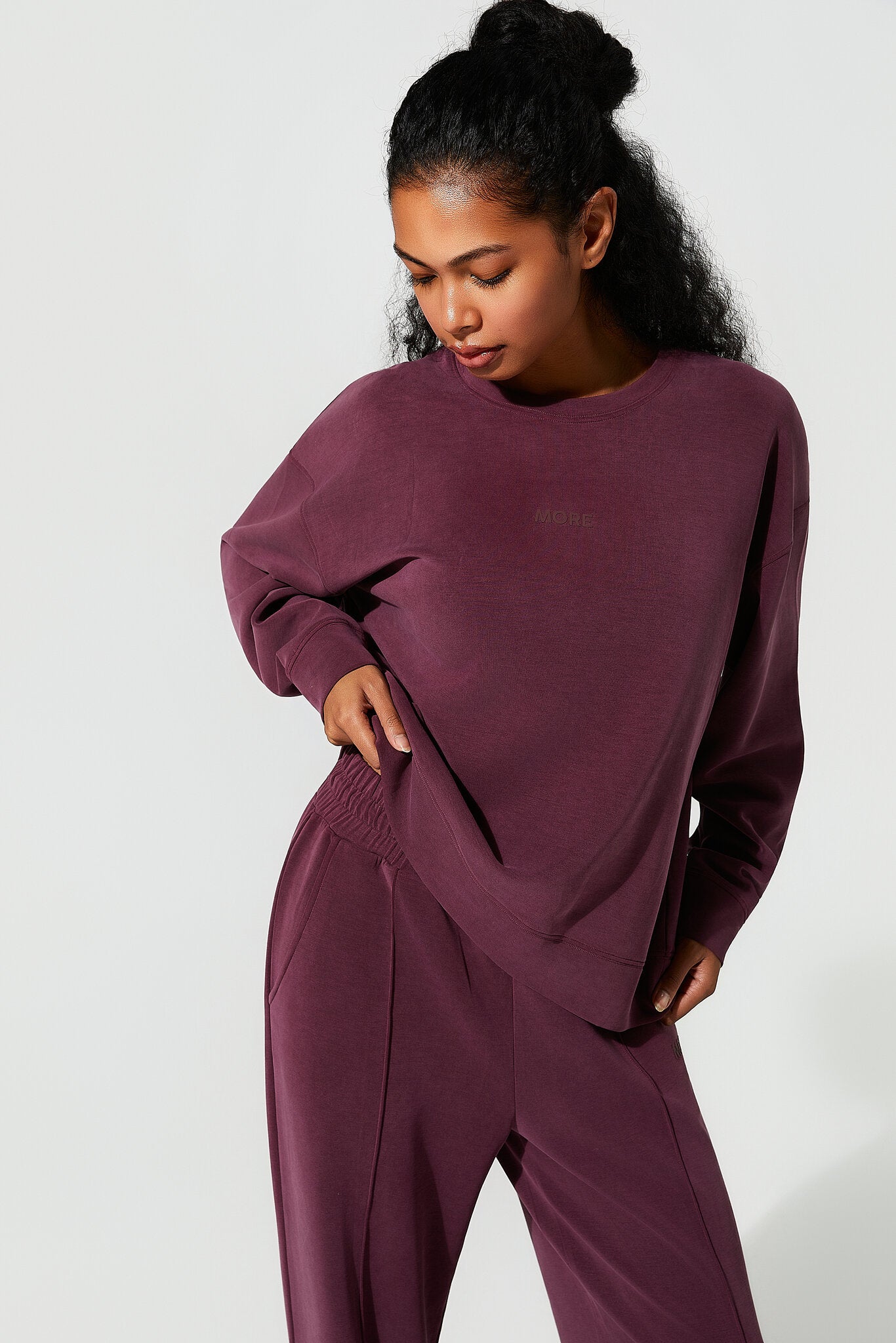 Woman wearing a maroon sweatshirt and pants set on a white background