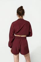 Person wearing a maroon tracksuit on a white background