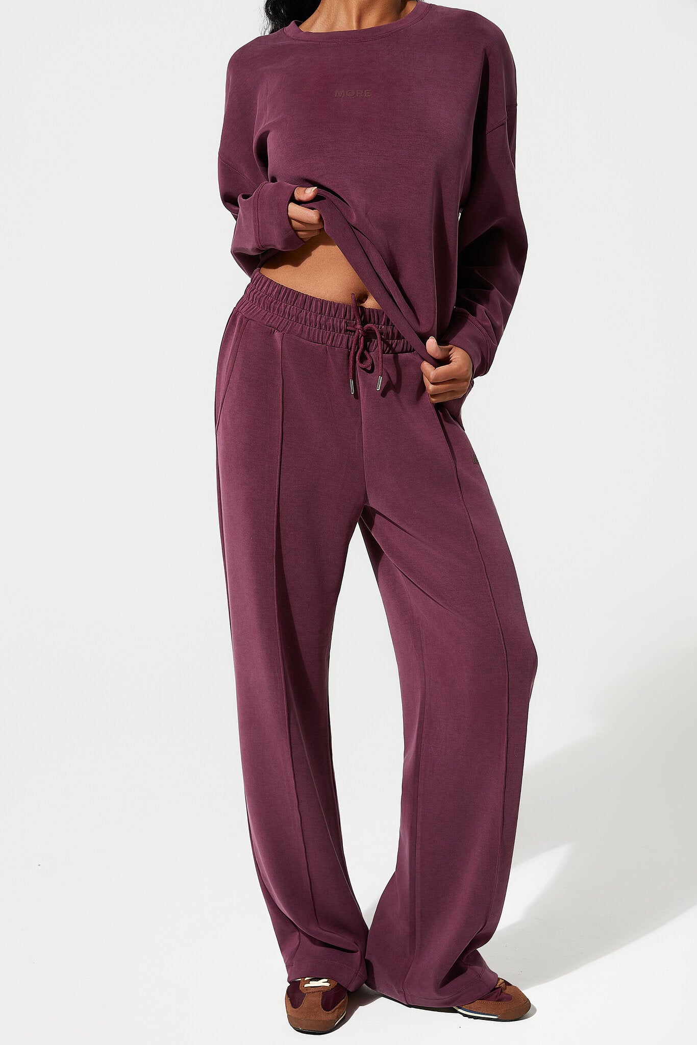 Person wearing a burgundy loungewear set on a white background