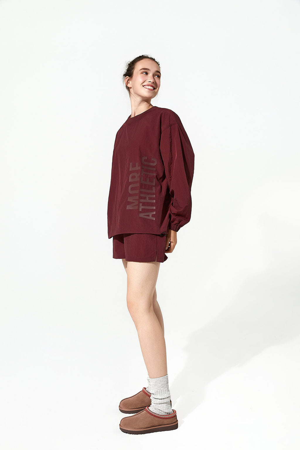 Person wearing a burgundy oversized sweatshirt and shorts set on a white background