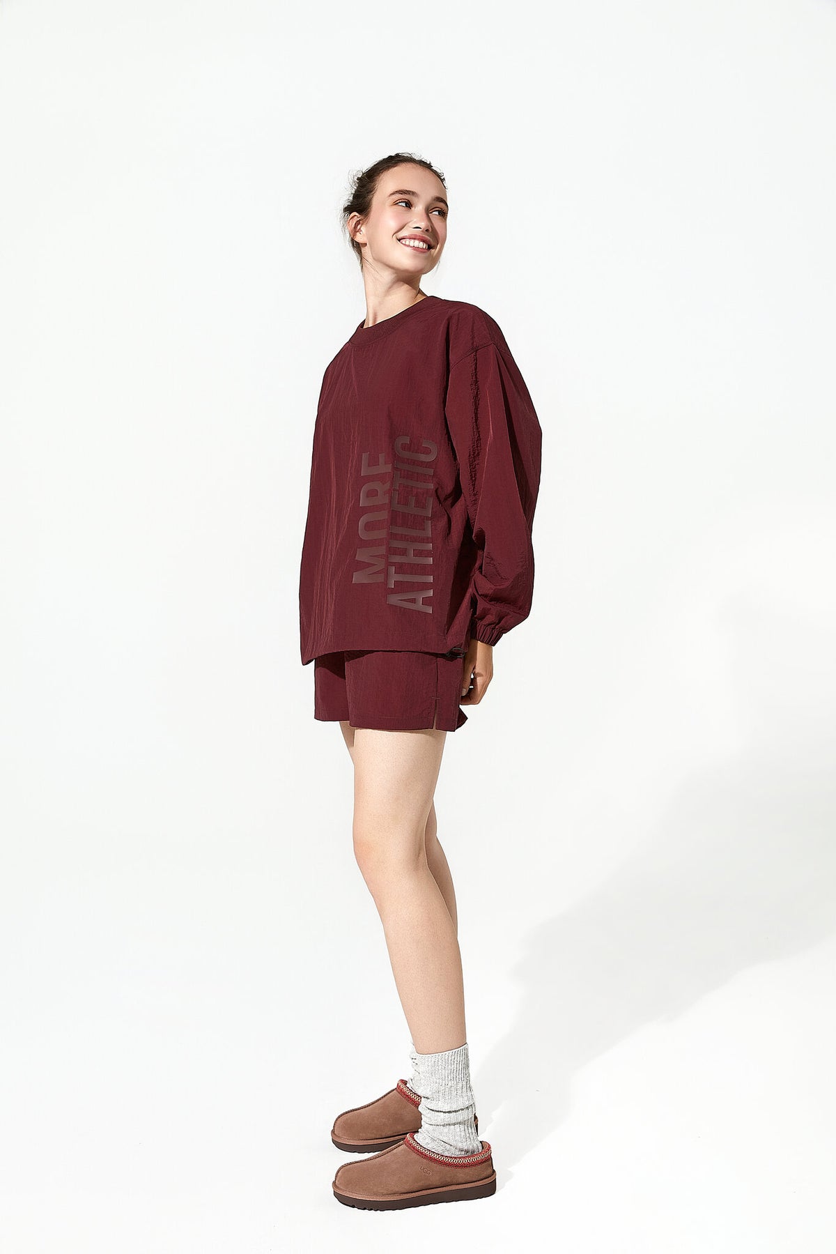 Person wearing a burgundy oversized sweatshirt and shorts set on a white background