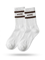 Pair of white half-crew throwback socks with a chocolate brown double stripe and MORE wordmark, flat lay