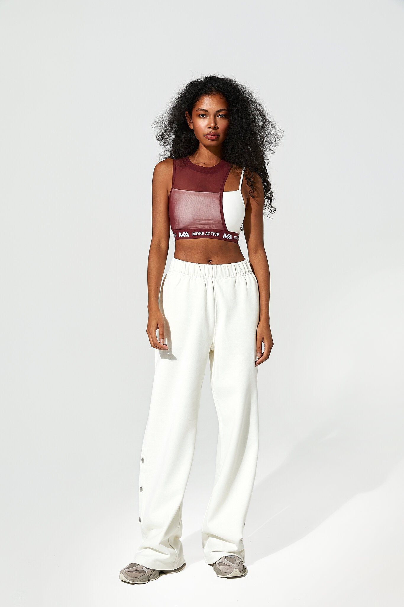 Woman wearing a colorful top and white pants on a white background