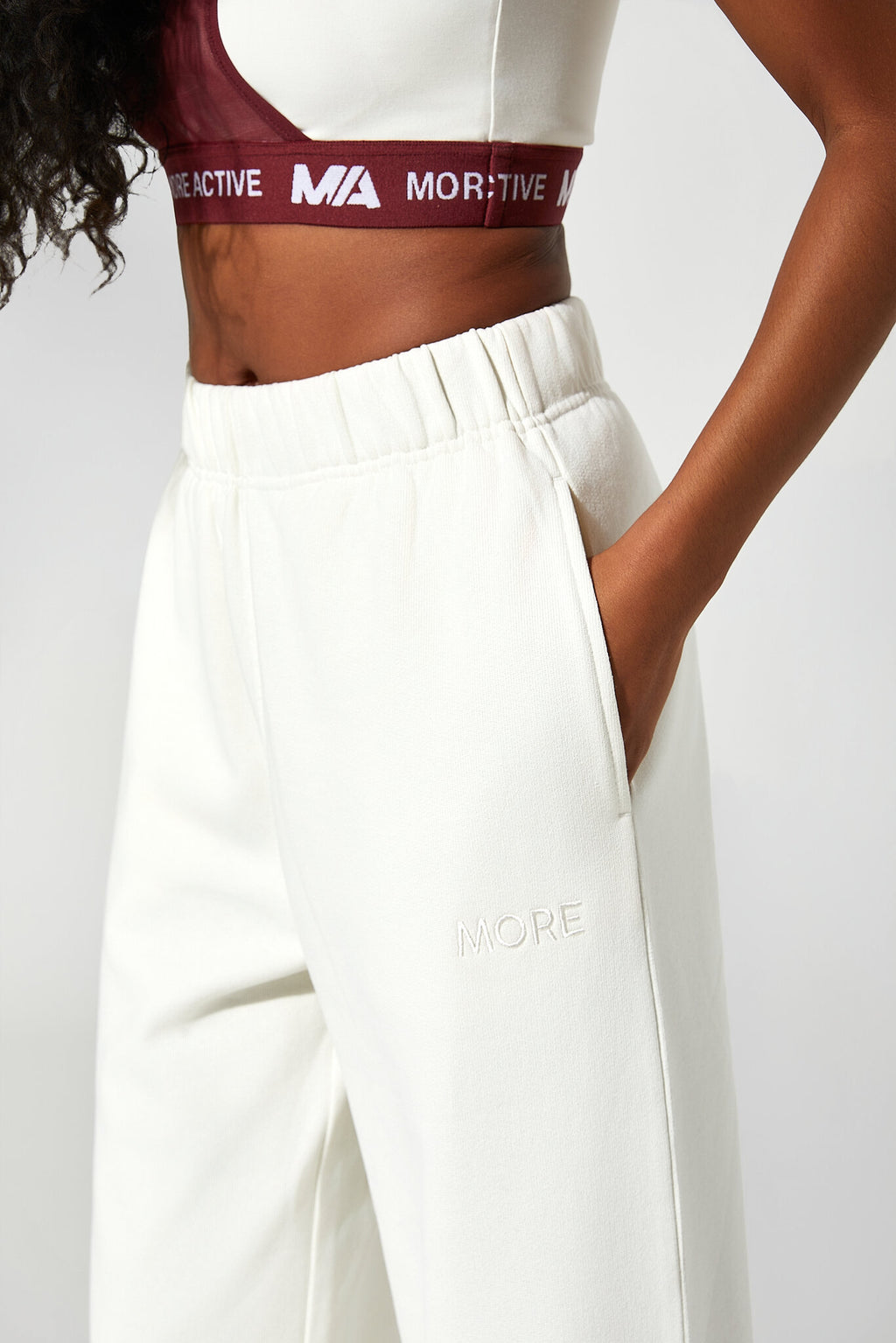 Person wearing a white sports bra and pants with visible branding on a plain background