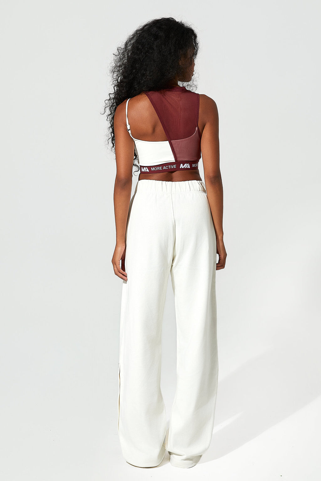 Woman wearing a white jumpsuit with a sheer red top on a white background