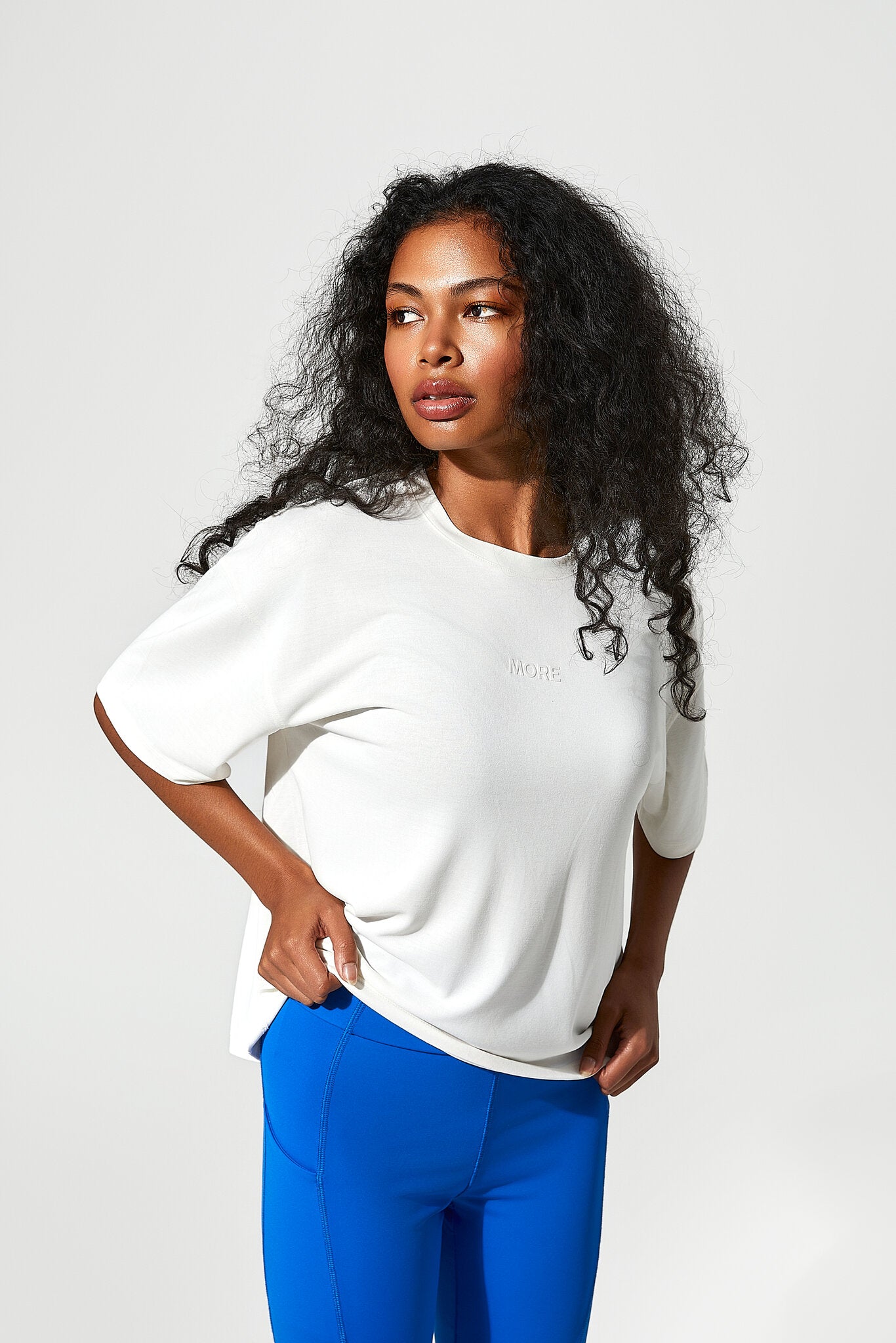 Woman wearing a white top and blue pants on a light gray background