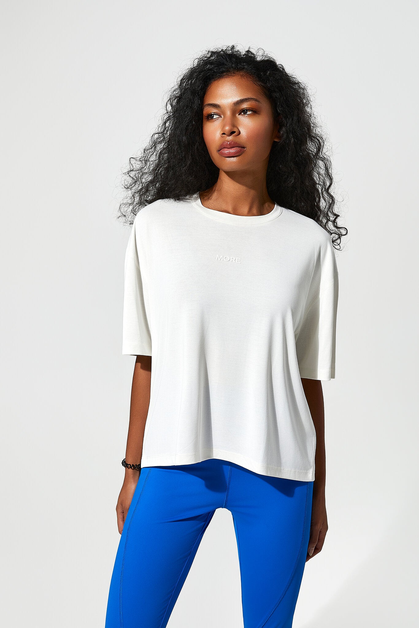 Woman wearing a white top and blue pants on a light gray background