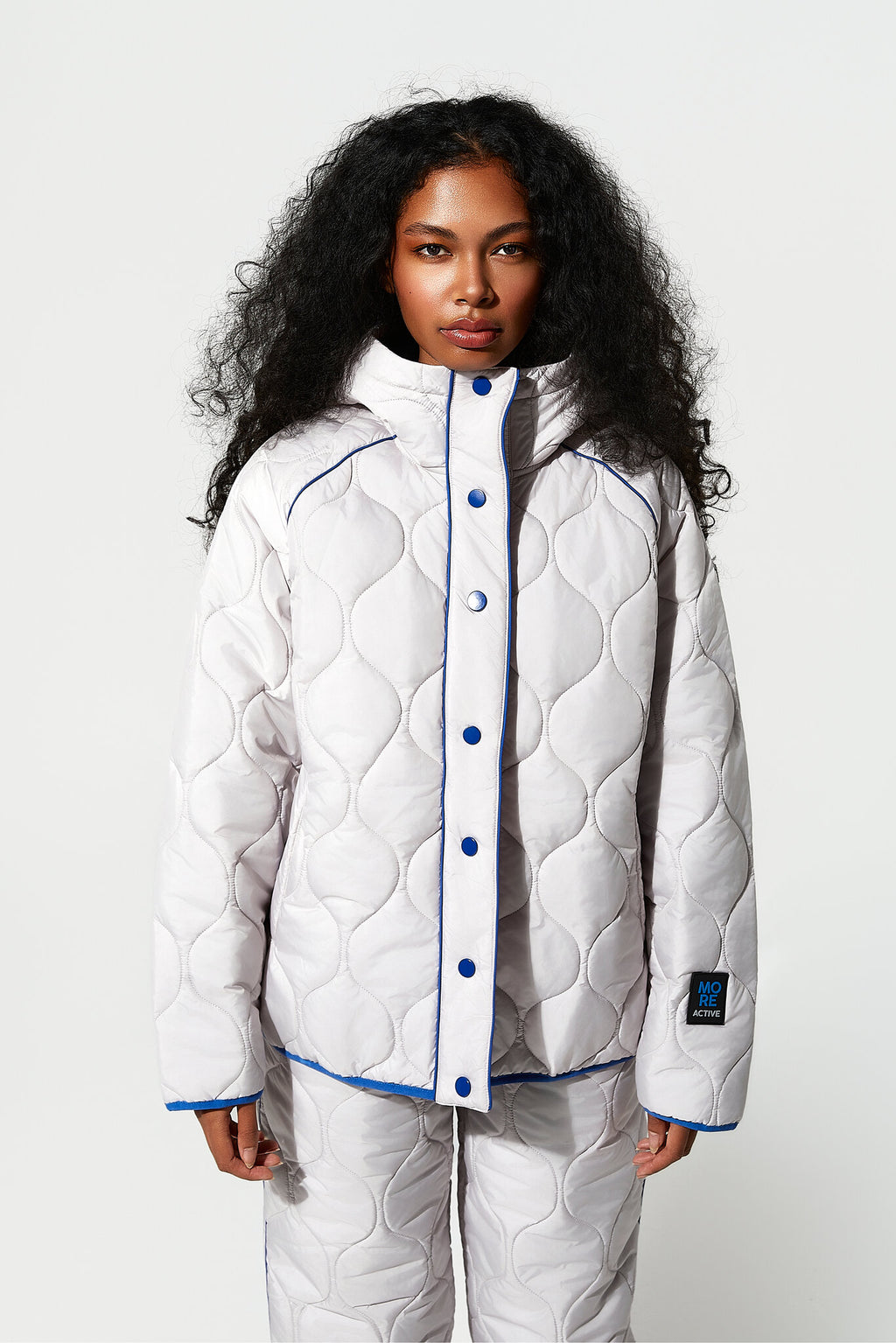 Person wearing a white quilted jacket with blue buttons on a white background